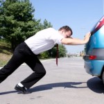 Businessman pushing a broken car business struggle