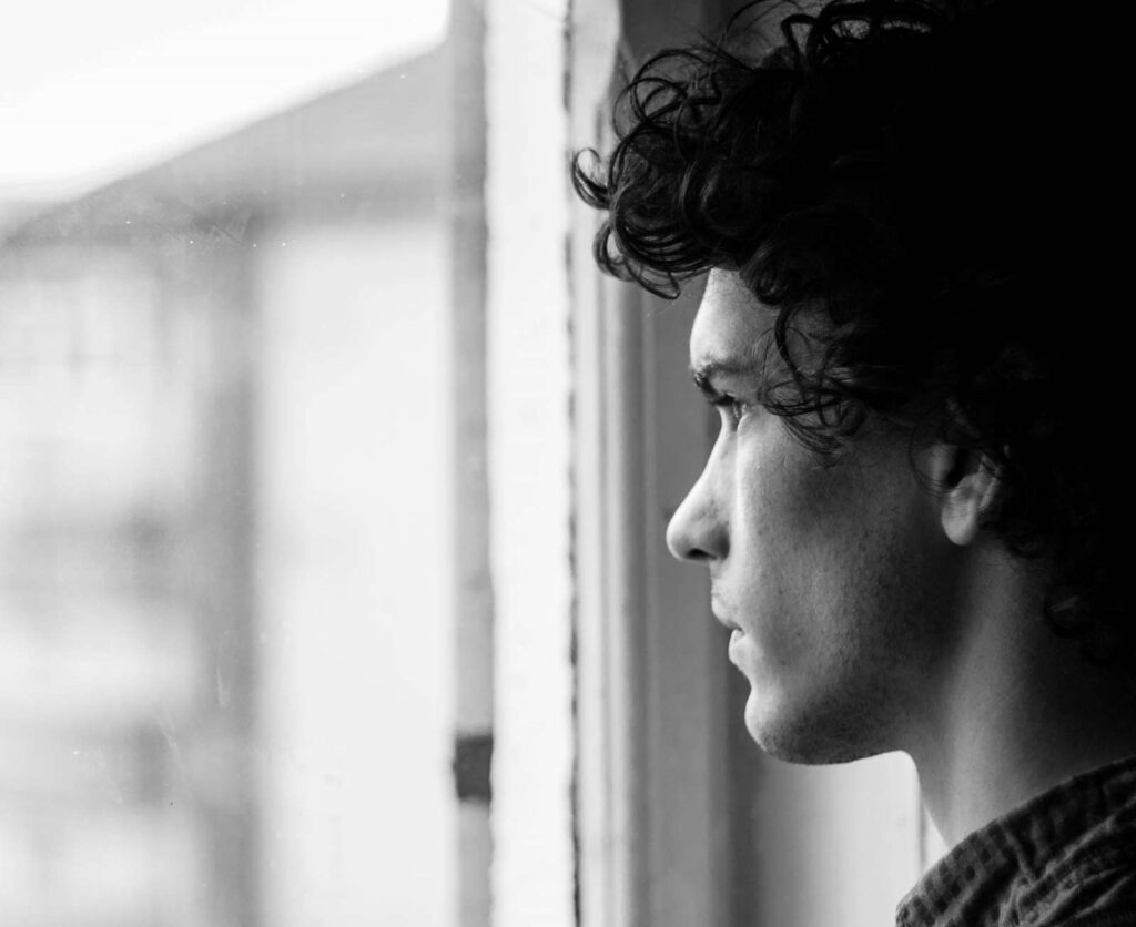 black and white photo of person looking out window reflectively