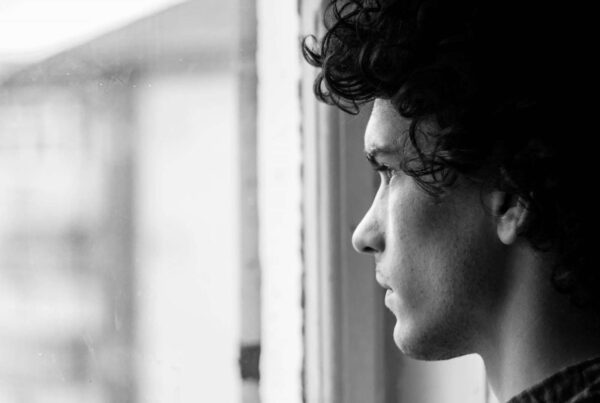 black and white photo of person looking out window reflectively