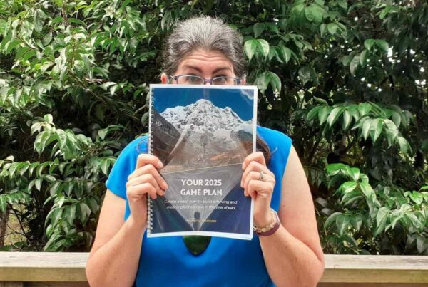 Kim Baird holding up Your 2025 Game Plan book