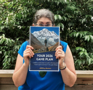Kim Baird holds a copy of Your 2026 Game Plan, a guided planning book to help you strategically plan for the year ahead